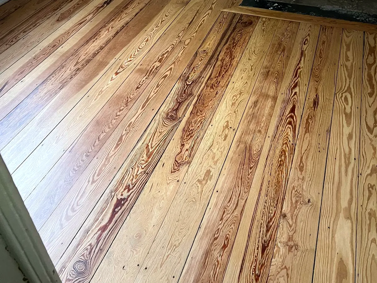 Le plancher en pitchpin poncé, teinte miel retrouvée près de la porte, chantier Wood Floors